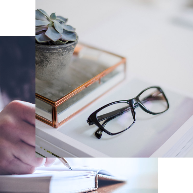 glasses on a table and a hand journaling